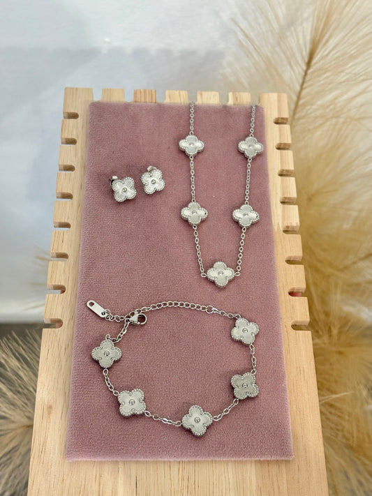 3-piece silver stainless steel jewelry set featuring textured guilloche four-leaf clover 5-motif necklace, stud earrings, and matching bracelet on a mauve display.⁠