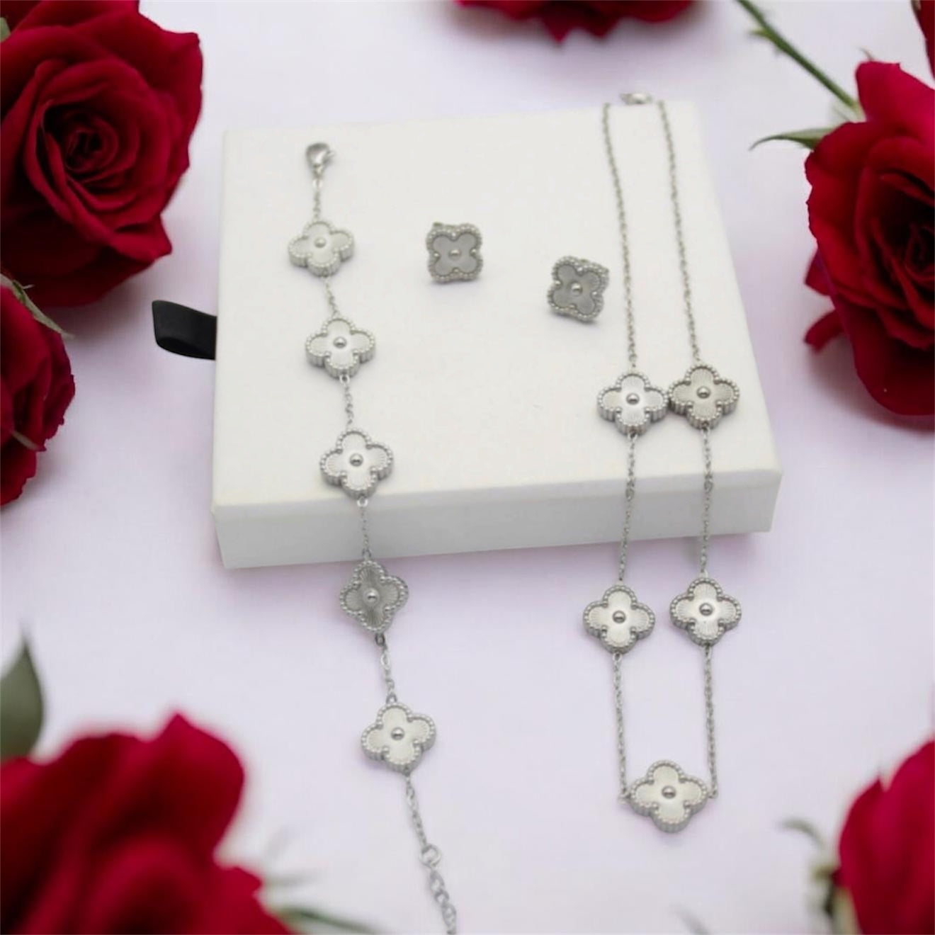 3-piece silver stainless steel jewelry set featuring textured guilloche four-leaf clover 5-motif necklace, stud earrings, and matching bracelet on a mauve display.⁠